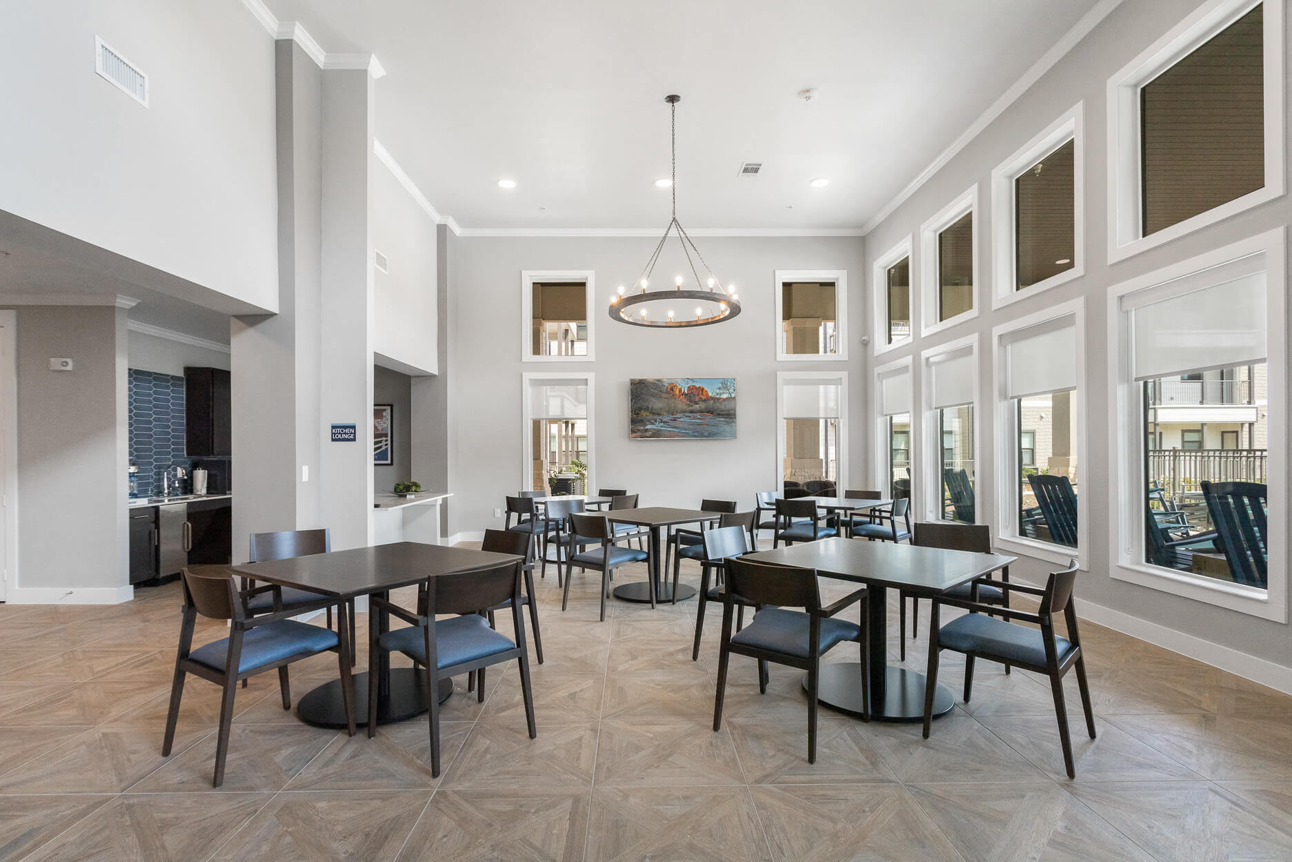 a communal clubhouse dining area with tables and chairs and a chandelier at a senior apartment community